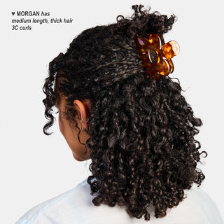 Honey tortoiseshell flower claw clip on curly hair at the crown.