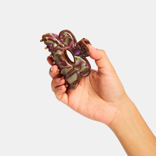 Purple marbled flower hair claw clip held in hand, oval opening visible