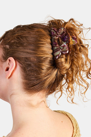 Purple marbled flower hair claw clip holding a curly bun, side view