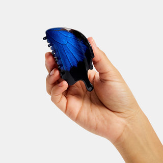 Swallowtail butterfly claw hair clip held in hand, blue wings on black base