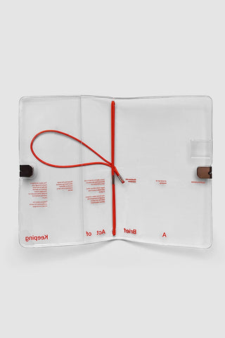 Clear vinyl travel notebook cover with elastic strap and black closure clips, pocket window