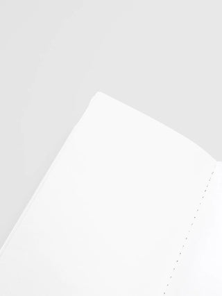 Close-up of blank notebook page corner with dotted stitching