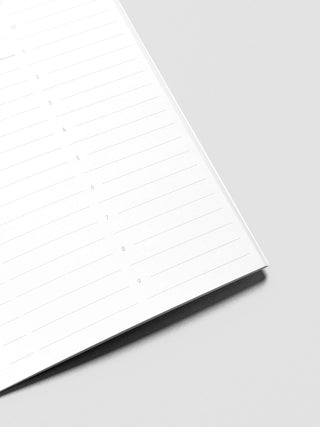 Slim lined notebook pages, white paper with black binding edge in a diagonal view.