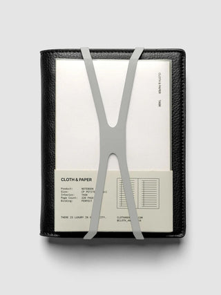 Black notebook with light gray V-shaped closure bands and rounded cutouts