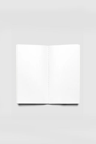 Blank travel notebook opened flat, white pages with stitched binding