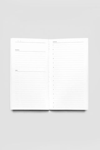 Open white daily lined travel notebook with two pages of horizontal lines