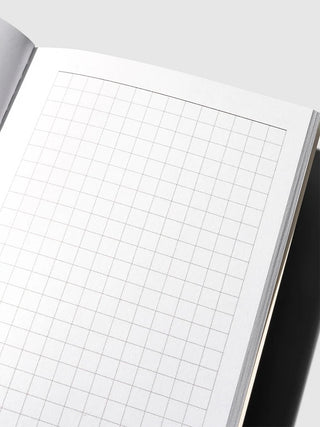 Close-up of weekly graph paper inside travel notebook with fine grid lines