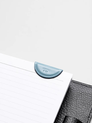 Light blue mini magnetic bookmark crescent clip on lined notebook page