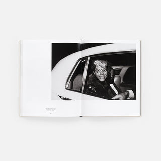 Open monograph book showing a black-and-white photo of a person inside a car