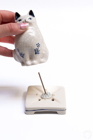 Cat porcelain incense burner with incense stick on square holder; cat held by hand
