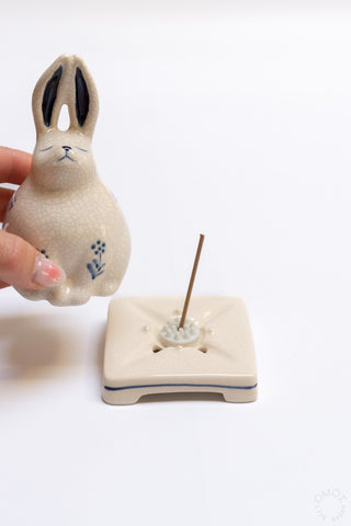 Porcelain rabbit incense burner with an incense stick and blue floral markings on base