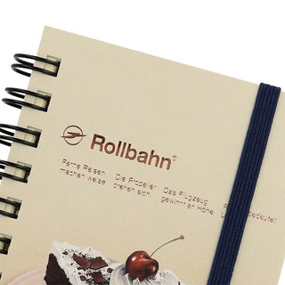 Large spiral notebook close-up, Rollbahn logo, cake illustration and blue fabric spine