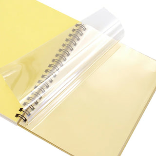 Large spiral notebook with cream pages, black rings, partially wrapped in clear plastic