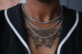 Layered box chain necklaces in silver-tone on a person’s neck with close-up view