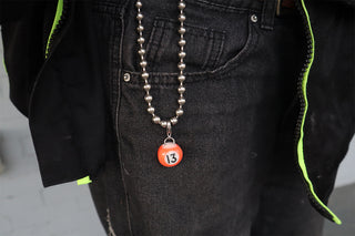 Person wearing a chain with a #13 orange pool ball keychain