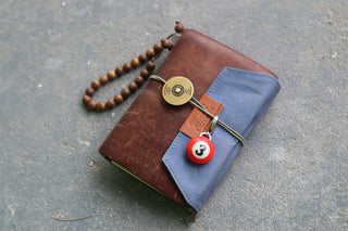 Brown and blue wallet with a red #3 pool ball keychain on a gray surface