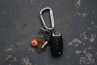 Keychain with keys and an orange #5 pool ball keychain on a textured dark surface