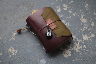 Brown leather wallet with a chain and #8 ball keychain on a textured surface