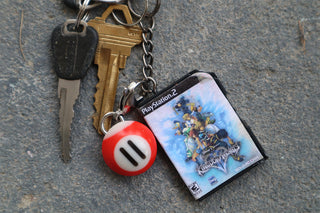 Keychain with a small game case and #11 red and white pool ball keychain on textured surface