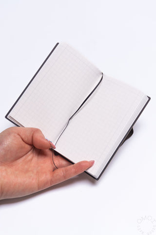 Open grid notebook with square pages and dark elastic spine