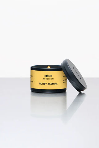 Honey jasmine tin candle in black and gold container, lid open showing flame