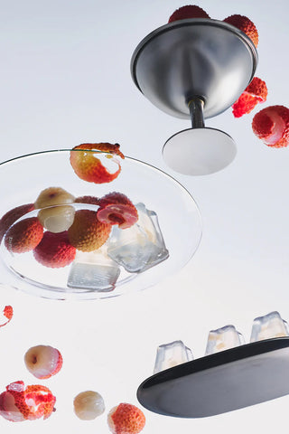 Lychee-scented tin candle with open lid and melting wax, with lychee pieces