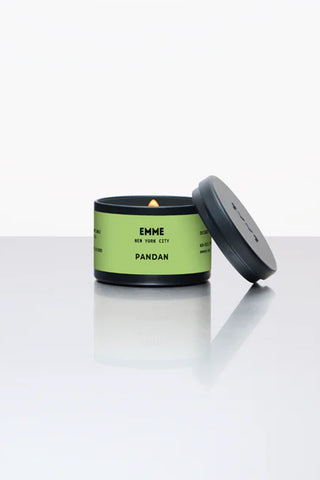 Pandan tin candle with lid open, lit wick in dark container with green label