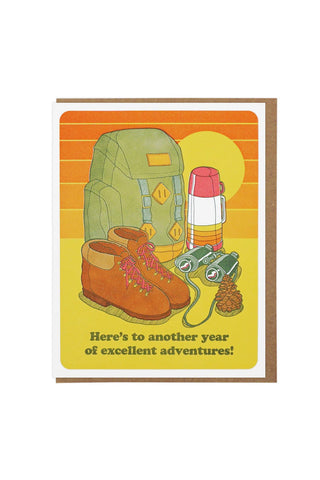 Birthday card with illustrated backpack, boots, and travel items; message 'Here's to another year...'