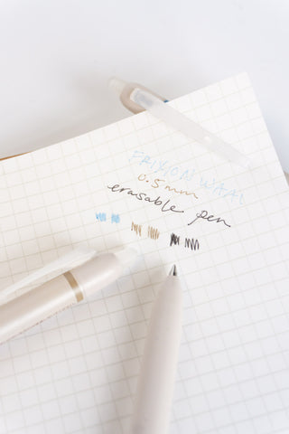 Erasable pen writing on grid notebook, blue marks and black scribbles