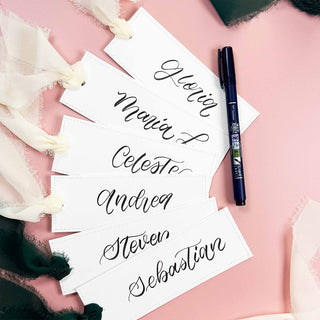 Dark blue brush pen writing cursive on stacked white cards