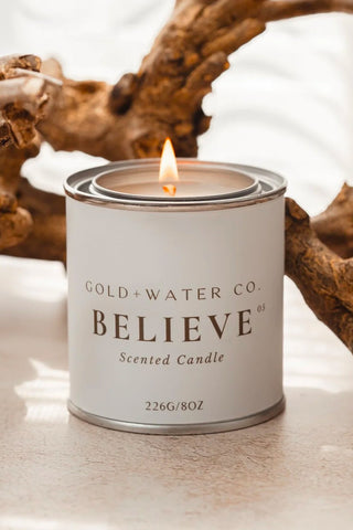 GOLD+WATER CO. BELIEVE No. 05 scented candle in a white metal tin with flame