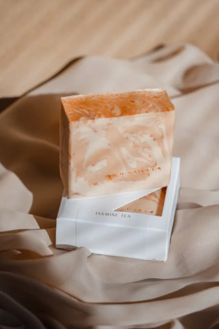 Handcrafted soap bar with jasmine tea label, shown in clear wrapping and paper sleeve