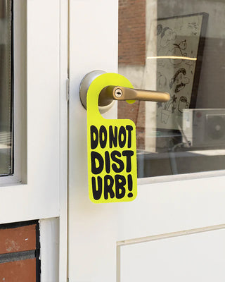 Rest room shoes hanging by a gold handle, black tags with bold yellow “DON’T DIS!” print