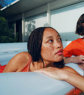 Person lounging outdoors with sunscreen applied to face and shoulders
