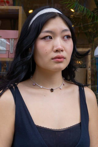 Silver teardrop bead necklace worn with dark sleeveless top, central dark drop pendant