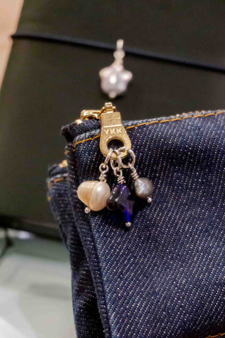Dangling charm set with blue heart, pearl bead, and silver accents on denim