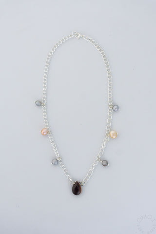 Silver chain teardrop necklace with dangling bead charms and central dark teardrop