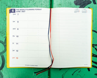 Open A5 weekly planner with weekly date schedule on left and blank lined notes on right