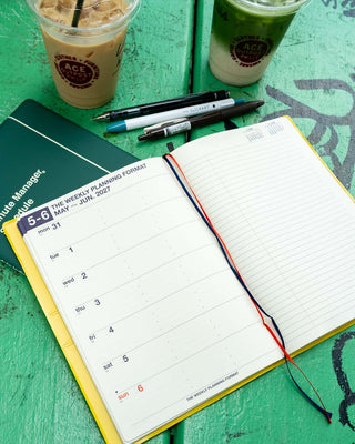 A5 weekly planner open with weekly date grid on left and blank lined page on right