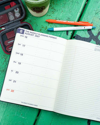 Open A5 weekly planner pages with printed weekly dates and lined writing area