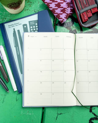 Open A5 monthly planner showing a calendar grid with date boxes