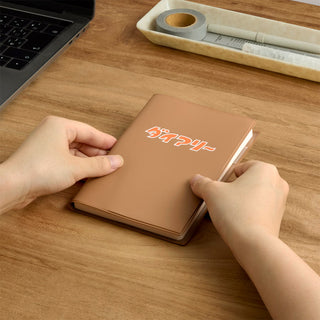 A6 weekly block planner, brown cover with orange logo, held closed