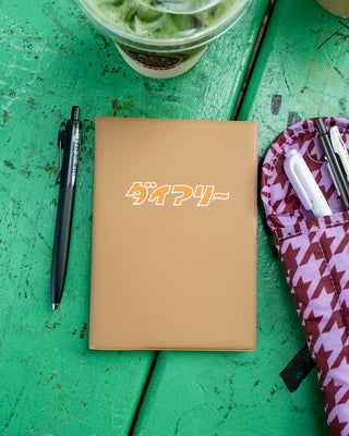 A6 weekly block planner, brown cover with orange logo, top view