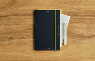 Navy B6 slim monthly planner with green bookmark ribbon and journal label
