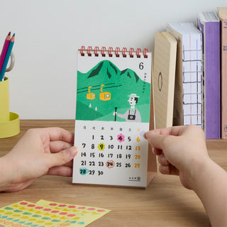 Desk calendar for month 6 with green mountain scene and colorful date numbers