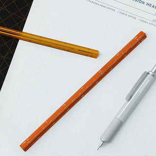 Orange aluminum metric drafting scale with measurement markings along the edge