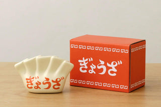 Porcelain dumpling pen holder, cream white with red Japanese characters, beside orange box