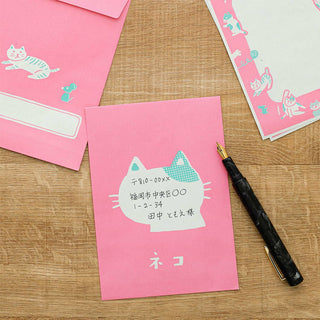 Pink cat letter cards and envelopes on wood, one with handwritten address label