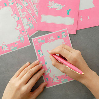 Pink cat patterned letter card with note being written with a pen