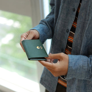 Green leather card case held in hand with stitched edges
